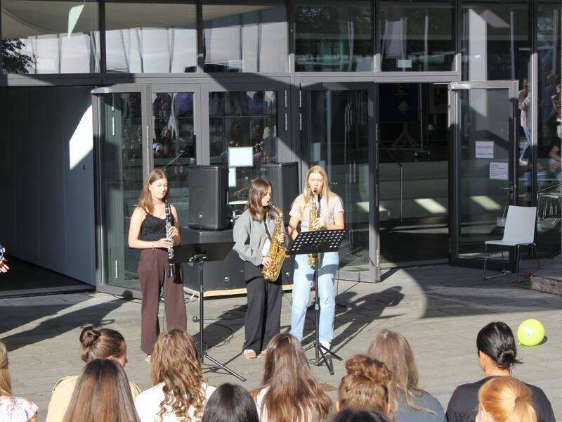 Eine Gruppe junger Musikerinnen spielt draußen vor einem Gebäude für ein Publikum.